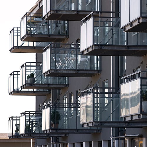 Inglasade balkongräcken med svarta profiler på ett lägenhetshus